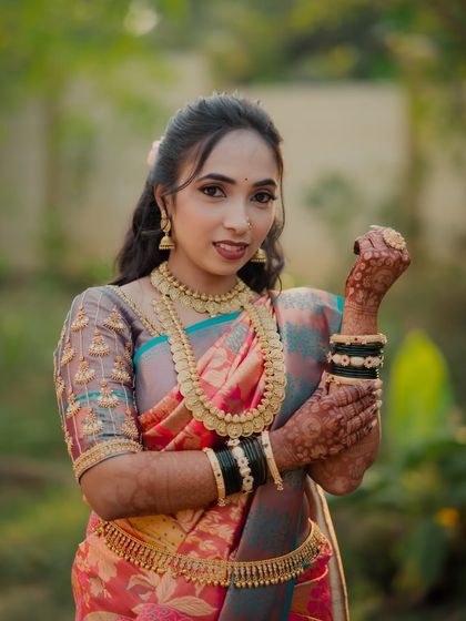 A beautiful portrait of the bride, showcasing her intricate temple jewelry and the detailed embroidery on her blouse. Her confident pose highlights her bridal elegance.