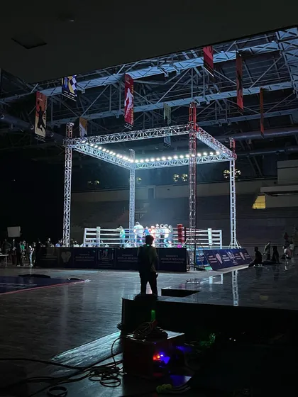 A silhouette of a person watching the activity in the brightly lit boxing ring. This image captures the scale and professional atmosphere of the events we host.