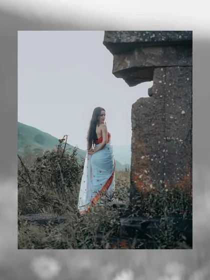 A mysterious and atmospheric shot, with the model in a Bengali saree standing near ancient stone ruins, creating a story-like feel.