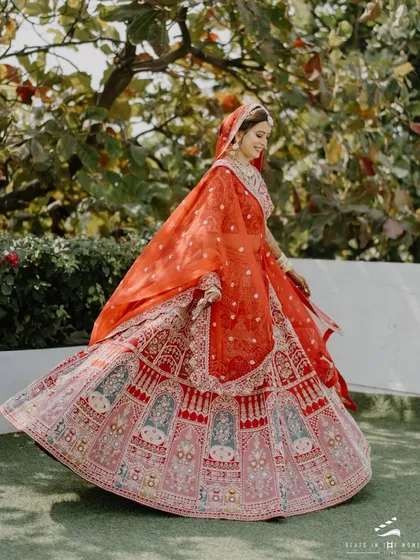 A bride twirls in her vibrant red lehenga, full of life and joy. This shot captures the beautiful movement of her outfit and her radiant happiness.