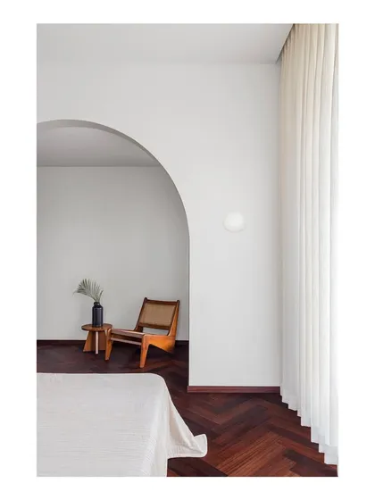 A master bedroom designed as a minimalist refuge. The simple archway creates a gentle transition into a quiet reading nook, demonstrating my belief that homes should provide spaces for peace and silence away from a frenetic world.