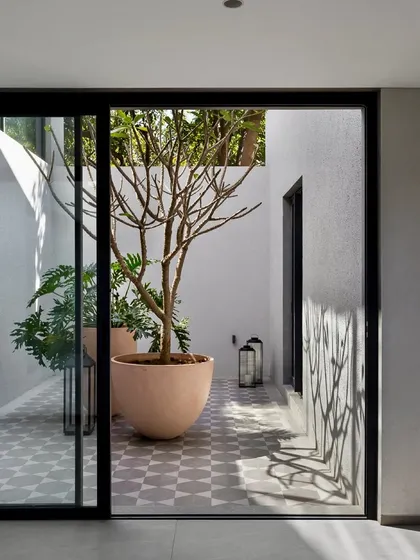 An open-to-sky courtyard brings light and nature into the very core of the Mango Orchard House. The patterned floor tiles and potted frangipani tree create a tranquil, contemplative focal point.