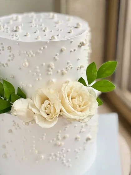 A detailed close-up of the fresh white roses and edible pearls. This view shows the texture of the buttercream and the careful arrangement of each decorative element.