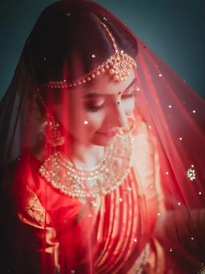 The timeless beauty of a bride. This portrait uses soft, focused light to highlight the delicate details of her traditional attire, the rich color of her veil, and her serene expression.