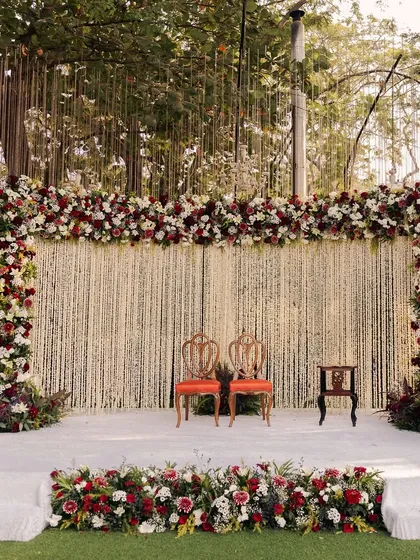 Classic elegance defined. This Parsi wedding stage features a dense backdrop of white rajnigandha strings, framed by a rich border of red and white roses for a timeless look.