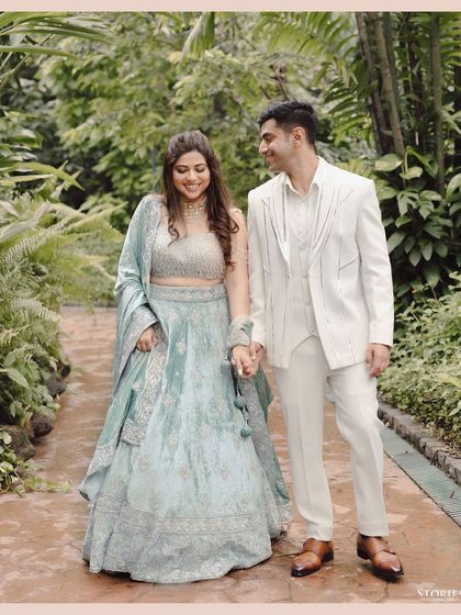The couple walking through a lush green pathway, sharing a laugh, a perfect candid moment.