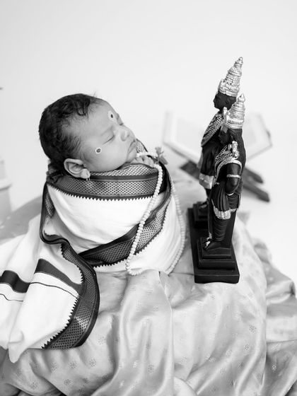 A side profile in black and white, showing the baby seemingly in devotion towards the Vitthal-Rukmini idols.
