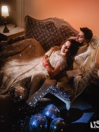 Another angle of the couple on the vintage sofa, this time from above. This perspective gives a sense of intimacy and quiet amidst the party atmosphere.