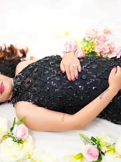 A beautiful flat-lay portrait of a mother-to-be in a black sequined gown, surrounded by flowers. This artistic angle captures her serene beauty and the elegance of the moment.