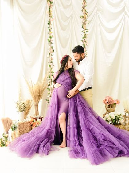 A full-length shot of the couple against our bright, floral swing backdrop. The purple ruffled gown is the star of the show, creating a dramatic and beautiful silhouette.