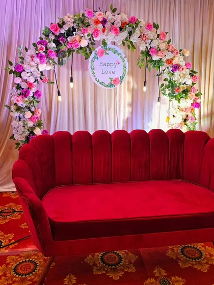 Another angle of the beautiful floral arch and red sofa combination. This view highlights the fullness of the rose arch and the rich texture of the velvet seating, perfect for capturing couple portraits.