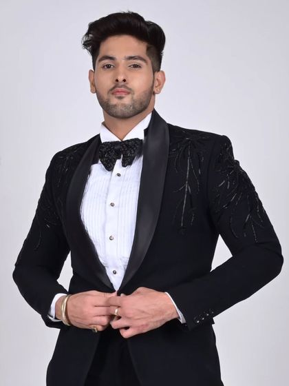 A confident pose in our custom black tuxedo. The fit is tailored to perfection, ensuring a sharp silhouette for any formal occasion.