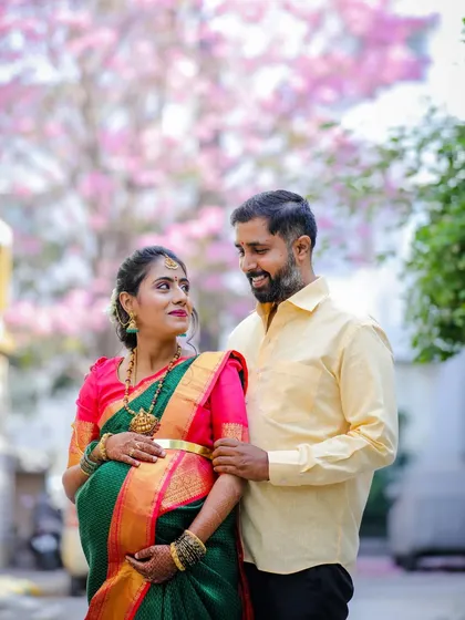 A romantic outdoor maternity shoot for a couple, set against the beautiful backdrop of Bangalore's blooming Tabebuia trees. This session highlights a natural, candid style that captures the couple's connection.