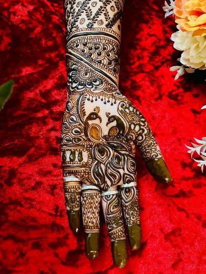 A close up of one hand from a bridal set, featuring two peacocks nestled among detailed feather and floral patterns. The fine line work is a testament to my dedication to quality.