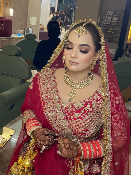 A close-up of the bride's makeup, showing the intricate details of her look. The hair is styled in a classic bun to support the heavy dupatta.