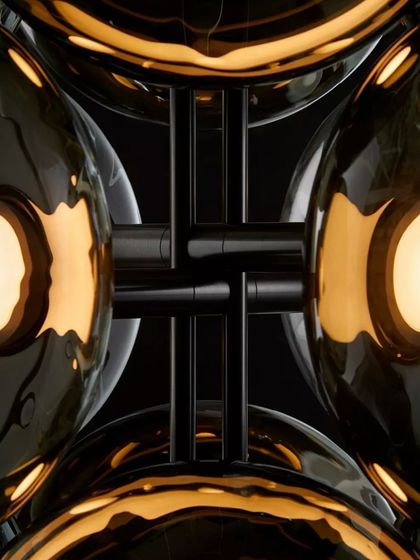 A detailed, abstract view of the Aeris fixture, showing the intersection of the glass spheres and the dark metal structure. The design creates a beautiful play of reflection and light.