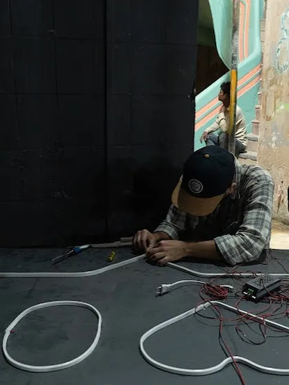 A work-in-progress shot showing the hands-on process of wiring the neon tubes for the installation. Every element is carefully assembled on site.