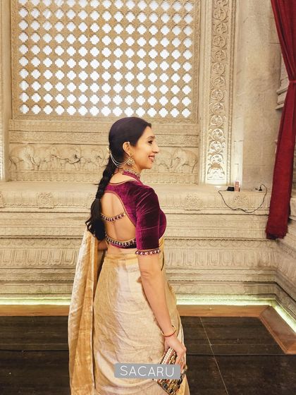 A wider shot of Krupa, showcasing the elegant drape of her saree and the striking back design of her magenta velvet blouse.
