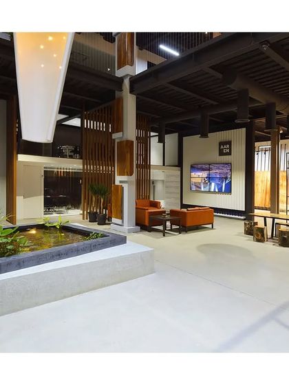 An interior view of a commercial space with an indoor water body and a mix of wood and metal elements. The design creates a unique and inspiring atmosphere that blends industrial and natural aesthetics.
