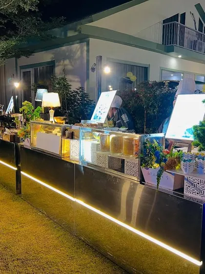 A long and beautifully lit buffet counter for an outdoor evening event, ensuring the food area is a highlight of the decor.