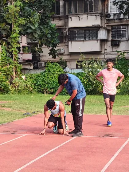 A normal day on the track, providing hands on correction for an athlete's starting position.