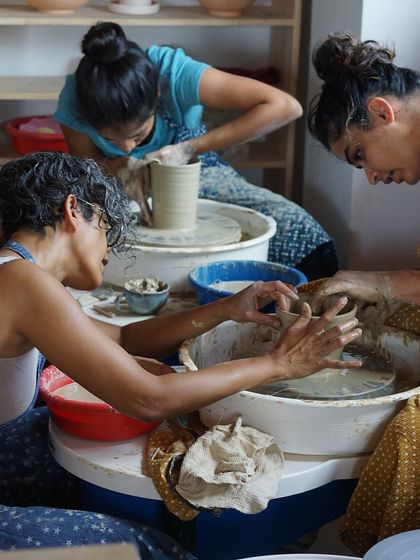 A view of three students working in unison at their wheels, a beautiful image of shared focus and creative energy.