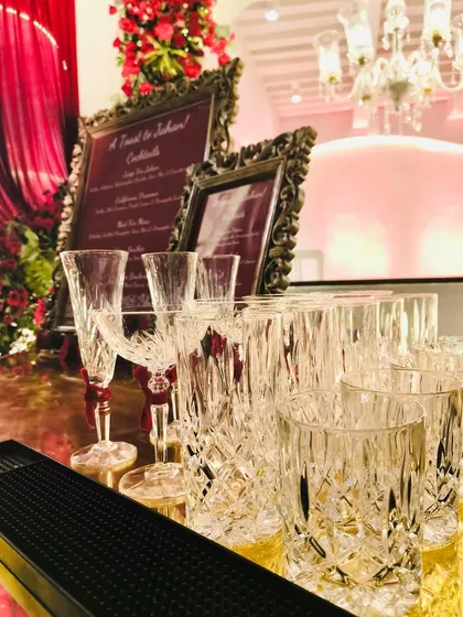 A close-up of the pristine, cut-crystal glassware ready for service. The intricate patterns of the glasses catch the light, adding a touch of sparkle and luxury to the bar top before the guests arrive.