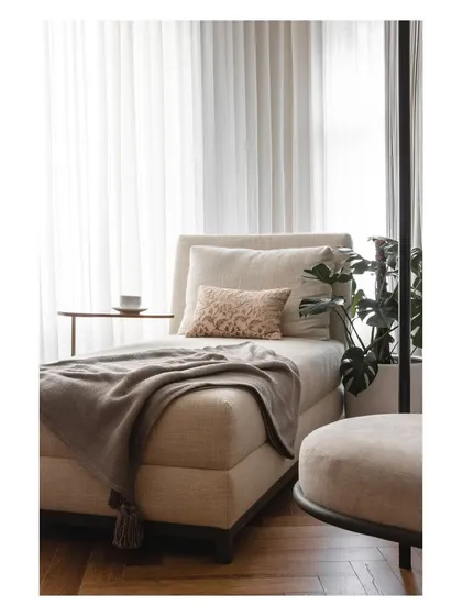 This cozy chaise lounge, placed by the window, is the perfect spot to unwind with a cup of tea and a good book.