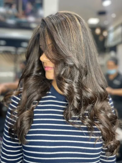 Voluminous curls showcasing a rich brunette base with subtle caramel highlights for a touch of warmth and dimension.