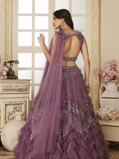 Shine like a princess in this stylish lavender lehenga with a ruffled skirt and a stunning open-back design. It’s a modern, glamorous choice for any evening event.