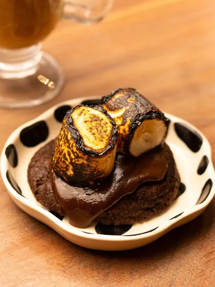 A close-up of a s'mores cookie from Mazi Cafe, with perfectly toasted marshmallows and rich chocolate sauce. The focus is on the gooey, decadent texture.
