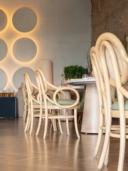 The interplay of surfaces at One 8 Commune. The warm wooden flooring in one section complements the backlit circular wall panels, creating a cozy and sophisticated dining nook.