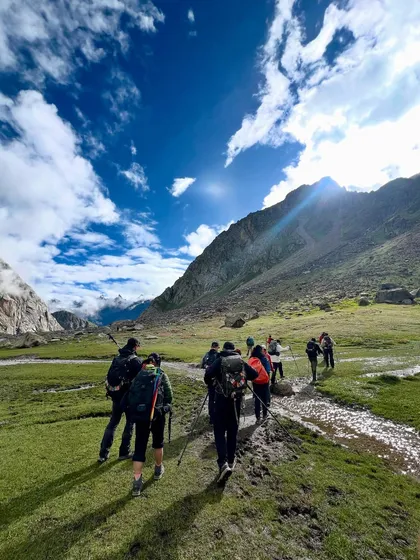 Walking through the vast meadows of the Hampta valley, with the trail stretching out ahead.