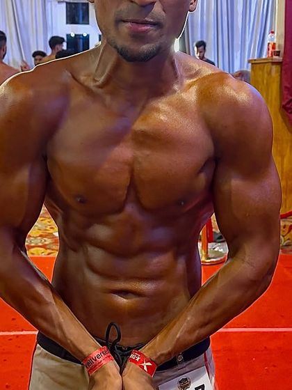 My client posing on stage. He evolved from an insecure beginner to a confident competitor, placing 5th in a large men's physique division.