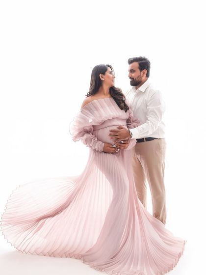 The delicate pleats of this light pink gown create a beautiful, flowing effect. This is a perfect example of a minimalist yet elegant studio maternity portrait.