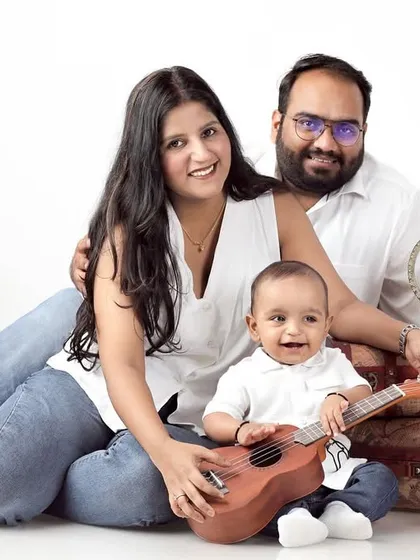A travel-themed family portrait, with parents and their one-year-old son posing with vintage suitcases and a globe.