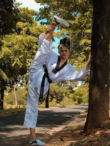 Using the environment to enhance training. A student uses a tree to deepen her stretch, demonstrating the creativity and dedication we encourage.