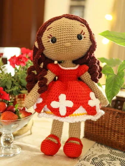 A full portrait of Lily the Doll, showcasing her handmade charm. Her simple, embroidered features and soft yarn construction make her a safe and gentle friend for young children.