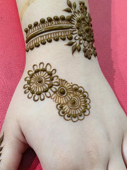 A very simple and minimal back-hand design, featuring just two small mandalas and a wristband. Perfect for a subtle and chic look.