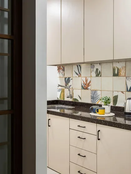 The office pantry is both stylish and functional. We used simple beige cabinets and a backsplash of playful, nature-inspired tiles to create a pleasant space for a coffee break.