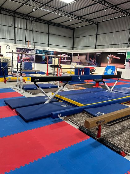 A view of our gymnastics facility, featuring balance beams, mats, and parallel bars. We have the professional equipment needed for serious training.