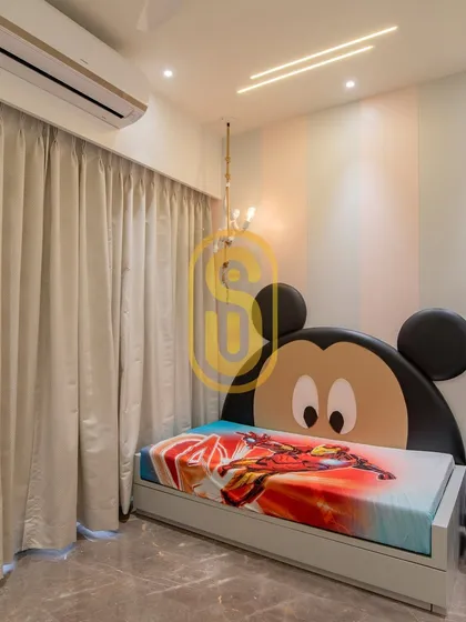 A fun and playful kids' bedroom we designed, featuring a custom Mickey Mouse-themed headboard. The striped wall and simple lighting make it a cheerful space for a child to grow in.
