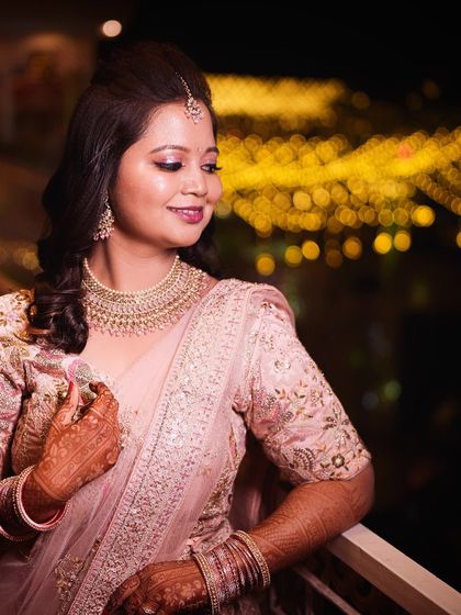 A beautiful shot of Kajol on her reception night. Her soft pink lehenga is paired with a glowing, romantic makeup look, perfect against the backdrop of city lights.