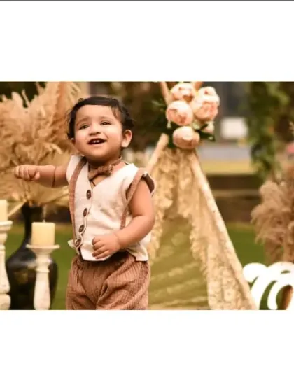 A happy one-year-old stands and points during his outdoor birthday photoshoot. The freedom of an outdoor space allows for natural movement and expression.