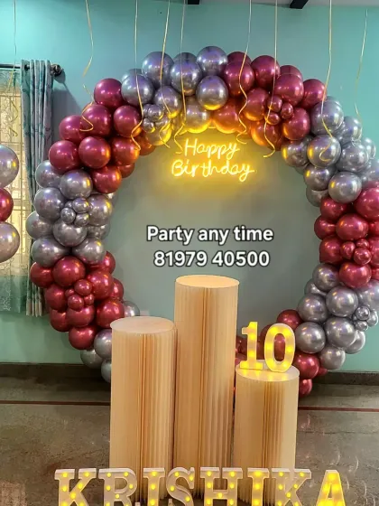 A 10th birthday setup for Krishika with a full ring of red chrome and silver balloons, a neon sign, and light-up name letters.