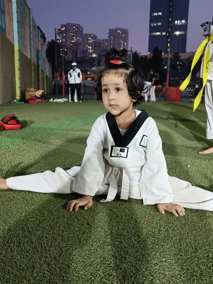 Anika holds her split, showing incredible progress and determination. This level of flexibility is achieved through consistent practice and is essential for advanced Taekwondo kicks.