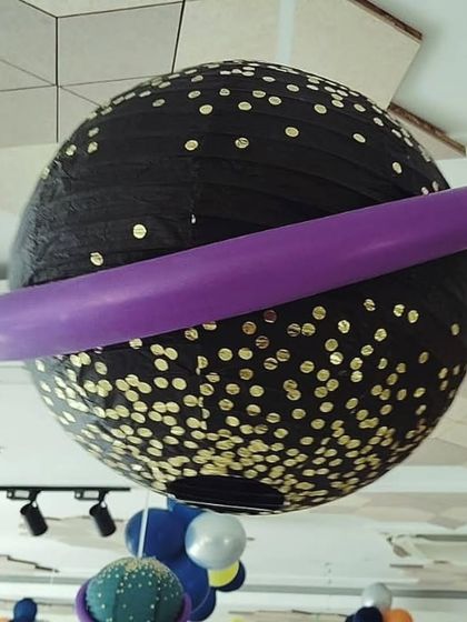 A creative hanging planet decoration made from a paper lantern and a balloon, perfect for a space-themed party.
