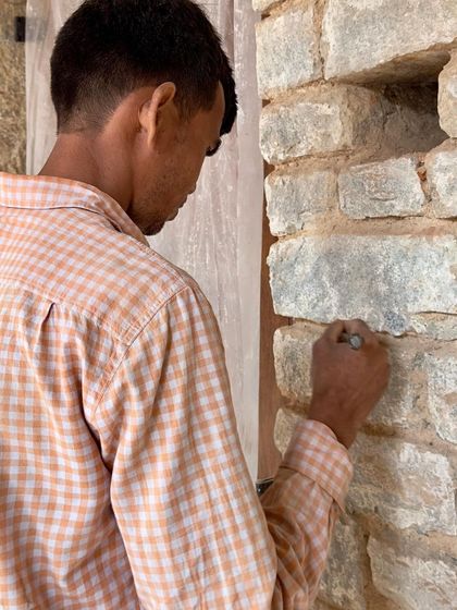 A craftsman carefully points the joints of the original stone wall. This traditional technique, using a lime-based mortar, is crucial for allowing the historic masonry to breathe and ensuring the long-term health of the structure.