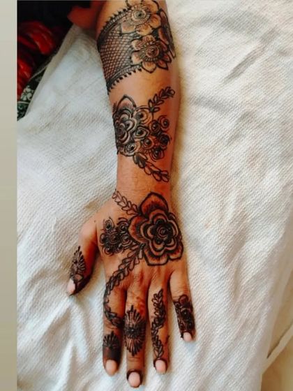 A beautiful floral vine design that covers the entire arm, with delicate chains and flowers on the hand.