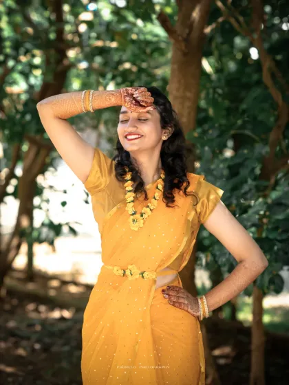 A radiant bride basking in the sun, her yellow saree and floral jewelry perfectly matching the Haldi theme.